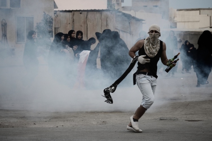 Bahrain: Un manifestant musulman şiit, ţinând în mână cocktail-uri Molotov, încearcă să se ascundă de gazul lacrimogen lansat de forţele de ordine în timpul încleştărilor declanşate după o demonstraţie antiguvernamentală în Bahrain (arhivă) (Mohammed al-Shaikh / AFP / Getty Images)