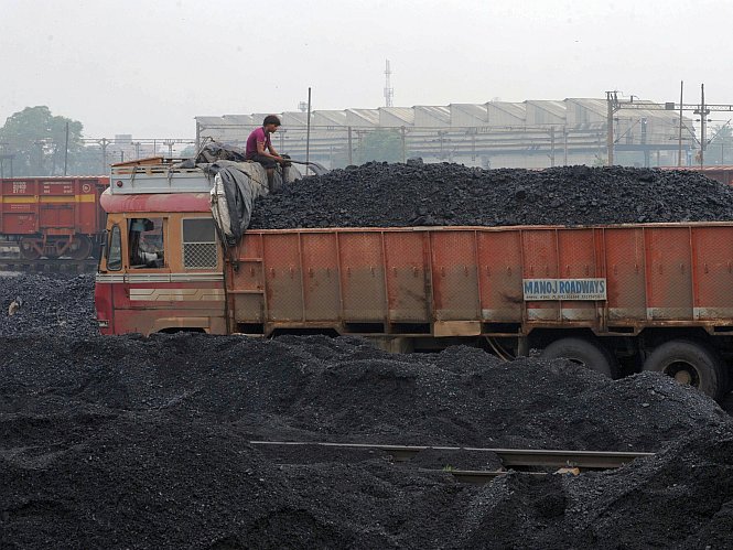 Un muncitor indian ia o pauză după ce a încărcat cărbune în camioane la Depoul Kankaria din Ahmedabad. India a propus deschiderea a 455 de centrale cu cărbune pentru a-şi satisface cererile energetice.