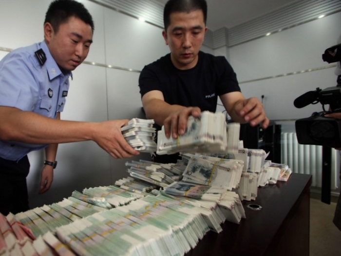 Ofiţerii chinezi de poliţie prezintă bancnote false în valoare de peste 6,6 milioane de yuani în cadrul unei conferinţe de presă, la Beijing, 10 iulie 2009. Cetăţenii chinezi i-au condamnat pe falsificatorii care au plătit pentru produsele organizaţiilor străine de caritate cu bani fără valoare. (AFP / AFP / Getty Images)