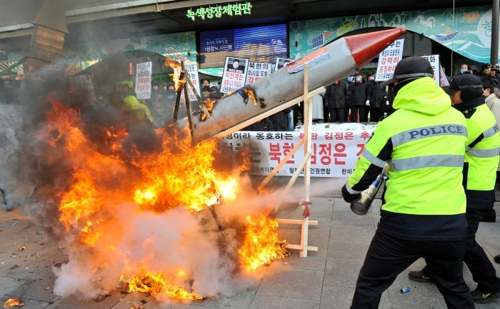 Poliţiştii sting focul provocat de un grup de activişti din Coreea de Sud, în semn de protest faţă de lansarea de către RPD Coreeană a unui satelit folosind o rachetă balistică cu rază lungă de acţiune, 12 decembrie 2012