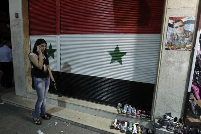 O femeie siriană vorbeşte la telefonul ei mobil în faţa unui magazin închis în districtul comercial al oraşului Homs.