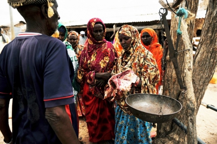 O somaleză inspectează carnea de cămilă pusă la vânzare
