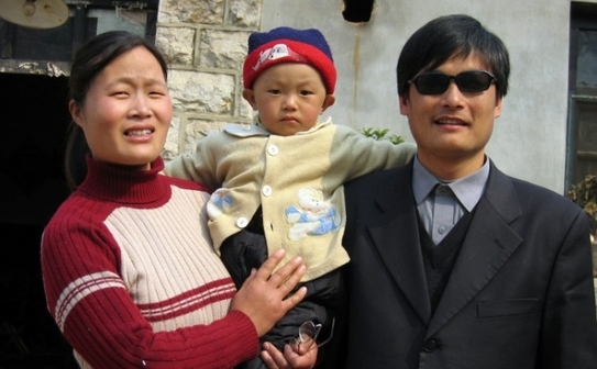 O fotografie din 28 Martie 2008 il infatiseaza pe activistul orb Chen Guangcheng (dreapta) alaturi de sotia si fiul sau Chen Keru, in fata casei, in satul Dondshigu, in provincia Shandong, in nord-estul Chinei. Conform asociatiei umanitare non profit ChinaAid, Chen se afla sub protectia Statelor Unite ale Americii in China. (STR / AFP / Getty Images)