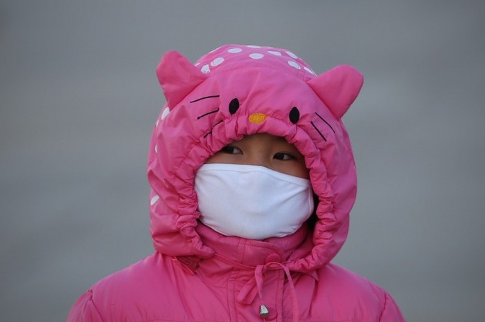 
O fetiţă poartă o mască în Piata Tiananmen pe 17 ianuarie 2013, în Beijing, pentru a o proteja împotriva poluării aerului.
