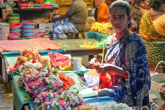 O femeie împleteşte şi vinde flori în piaţa de legume în Puducherry, India, 15 ianuarie 2013.