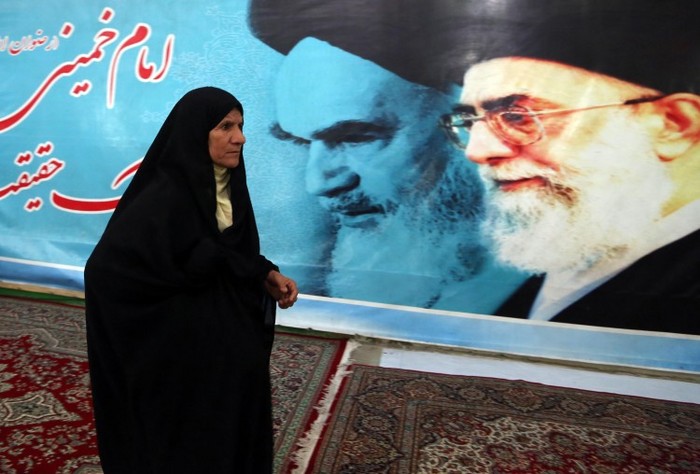 O femeie iraniană trece pe lângă un afiş gigant al fondatorului Republicii Islamice a Iranului, ayatollahul Ruhollah Khomeini şi conducătorul suprem, ayatollahul Khamenei Ali la 31 ianuarie 2013 în Teheran.