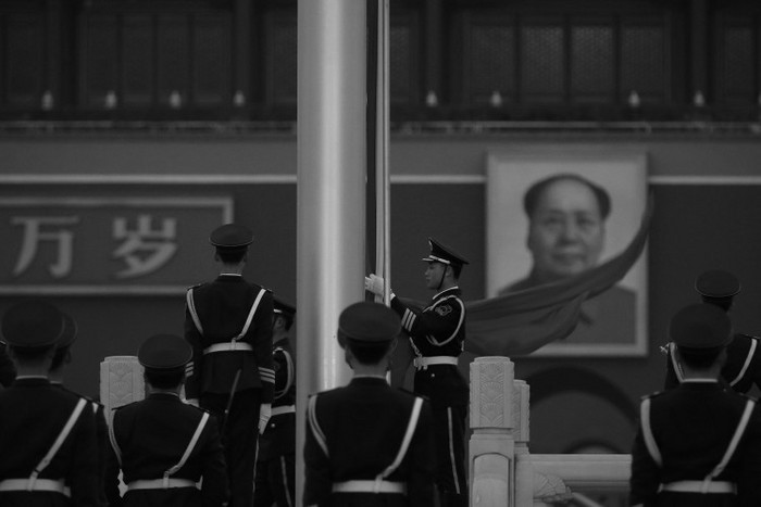 Un ofiţer de poliţie paramilitară strânge pavilion Republicii Populare Chineze în faţa portretului lui Mao Zedong din Piaţa Tiananmen din Beijing, la 2 martie. Televiziunea Centrală Chineză l-a citat recent pe Mao care preciza că el este dispus să vadă sute de milioane de chinezi ucişi.