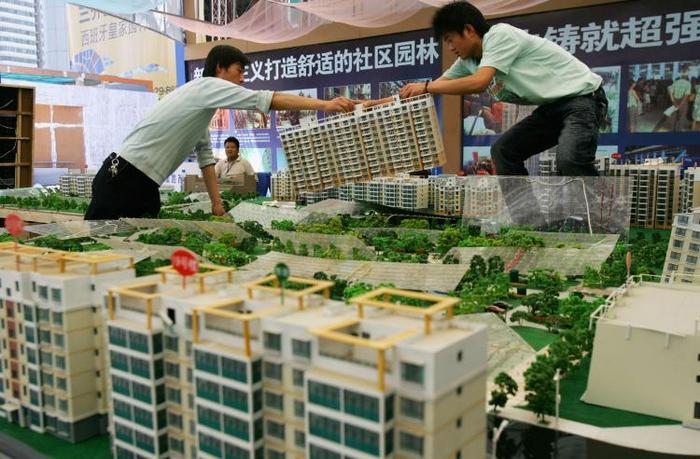 Doi muncitori mută un model de clădire în timpul unui targ imobiliar în 2007, în Xian, provincia Shaanxi, din China. Multe provincii din China au construit cartiere şi chiar oraşe  întregi care sunt, practic, goale.