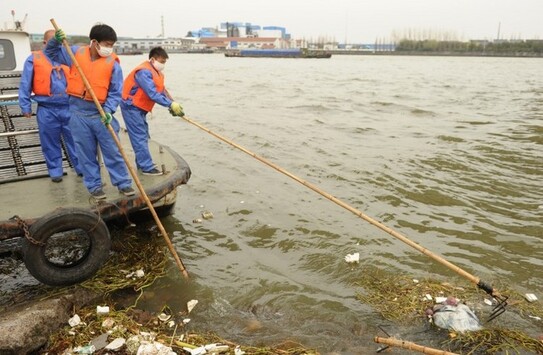 Anagajaţii de salubritate (stânga) colectează un porc mort de pe calea navigabilă principală din Shanghai, la 11 martie 2013. Aproape 6.000 de porci morţi au fost găsiţi plutind pe canalul navigabil principal din Shanghai, iar locuitorii şi-au exprimat temerile privind posibila contaminare a apei potabile. (Peter Parks / AFP / Getty Images)