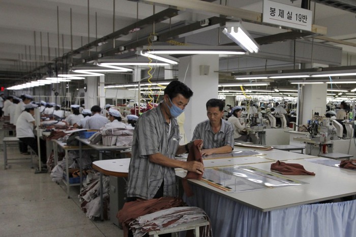 Doi bărbaţi nord-coreeni care lucrează pentru Shinwon, un producator sud-coreean de îmbrăcăminte, la o fabrică din Kaesong, Coreea de Nord în 2012 (AP Photo / Jean H. Lee, File)