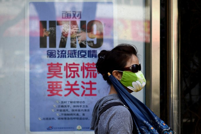 O femeie care poartă o mască de faţă trece pe lângă un afiş în care este explicat modul de evitare a virusului gripei aviare H7N9, în Beijing, 24 aprilie 2013.