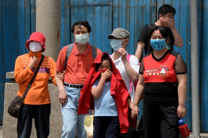 Oamenii poartă măşti pentru a se proteja împotriva poluării aerului şi a prafului din Beijing, 19 mai 2013.