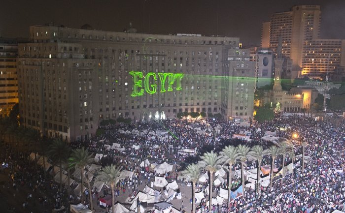 Protestatari egipteni cer demisia preşedintelui Mohamed Morsi în Piaţa Tahrir din Cairo, 2 iulie 2013. Raze laser proiectează pe clădirea guvernului cuvântul „Egipt” (DR). (KHALED DESOUKI / AFP / Getty Images)