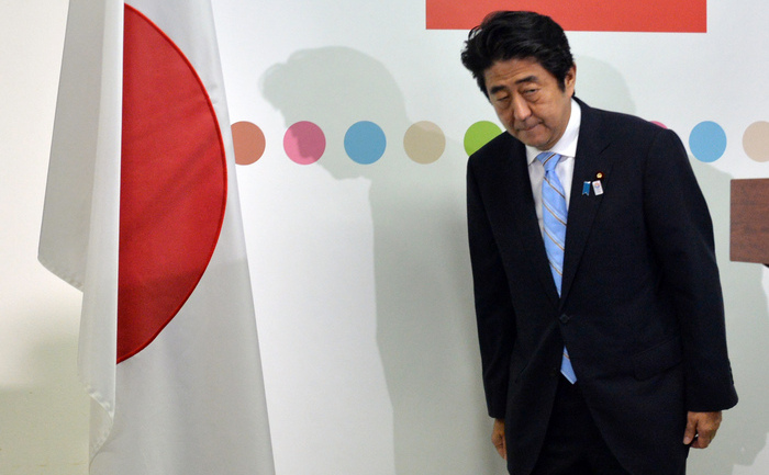 Premierul japonez Shinzo Abe se înclină steagului naţional japonez înainte de a începe o conferinţă de presă la Tokyo, pe 22 iulie 2013.