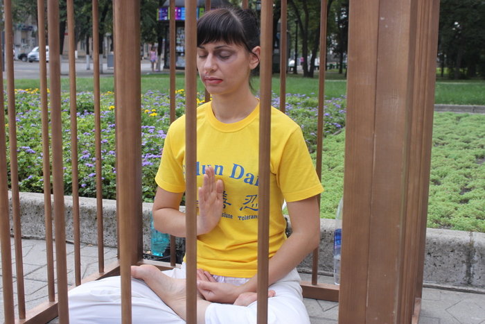 Reprezentant al Asociaţiei Obşteşti Falun Dafa din Republica Moldova înscenând una din sutele metode de tortură barbară la care continuă să fie supuşi discipolii Falun Gong din China doar pentru că îndeplinesc un set de exerciţii
