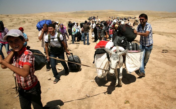Refugiaţii sirieni trec frontiera în regiunea autonomă kurdă din nordul Irakului, la 18 august 2013. Confruntându-se cu violenţă brutală şi creşterea preţurilor, mii de kurzi sirieni speră ca regiunea kurdă autonomă Irak să le ofere un răgaz de la privaţiuni şi lupte între kurzi şi jihadişti. (SAFIN HAMED / AFP / Getty Images)