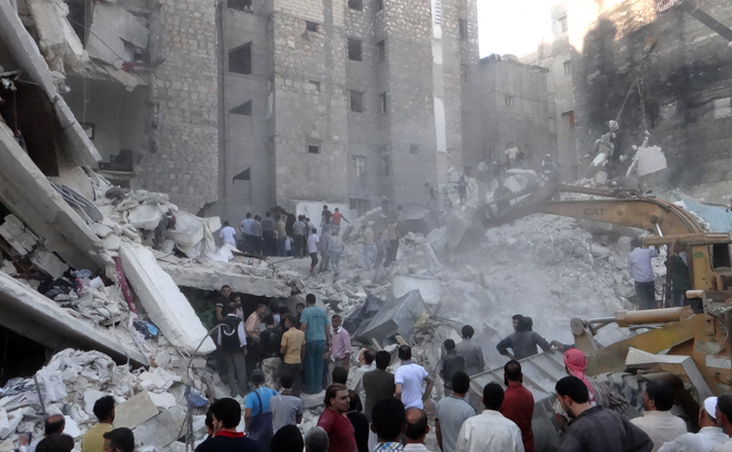 Siria: Oamenii se uită la un excavator care îndepărtează resturile dintr-o clădire care s-a prăbuşit după ce a fost bombardată de trupele pro-guvernamentale la 16 august 2013, în nordul oraşului sirian Alep. (FOUAD / AFP / Getty Images)