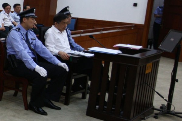 Cu o grimasă pe faţă, Bo se uită la judecător în timp ce stă cu un  picior peste altul, o postura ce indică puternic postura oficialilor  chinezi
