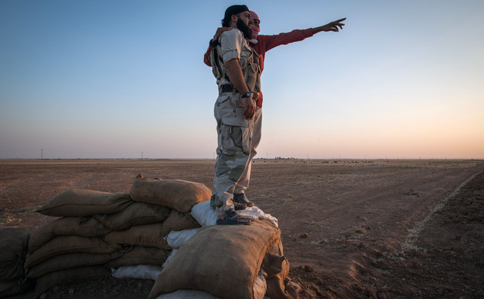 
Siria: Un bărbat neidentificat (fond) oferă informaţii unui rebel, în timpul ciocnirilor luptătorilor kurzi la marginea oraşului sirian Rojava, 23 august 2013.
