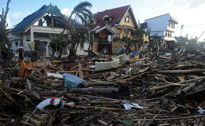 Oamenii merg printre moloz şi case distruse în Palo, estul insulei Leyte, 10 noiembrie 2013, la trei zile după ce devastatorul taifun Haiyan a lovit Filipine, la 8 noiembrie. (NOEL CELIS / AFP / Getty Images)