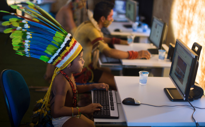 Un copil indigen se joacă la un calculator.