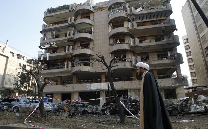 Un cleric şiit trece prin faţa unei cladiri avariate în urma dublului atentat sinucigaş cu bombă din faţa ambasadei Iranului la Beirut, 20 nov 2013. Ultimul bilanţ al victimelor indica 29 de morţi.