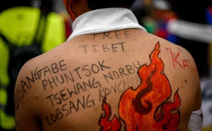 Un activist tibetan poartă pe umerii săi scris numele protestatarilor morţi care s-au auto-incendiat, 22 octombrie 2013, în faţa birourilor Naţiunilor Unite din Geneva.