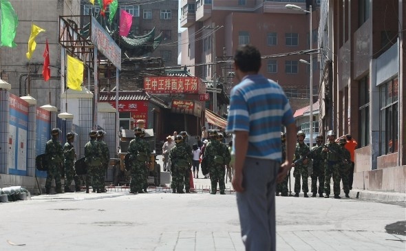 Atacul asupra secţiei de poliţie din Xinjiang este cel mai recent incident violent în această zonă din nord-vestul Chinei. În foto, un bărbat uigur se uită la poliţiştii chinezi ce blochează o stradă în 9 iulie 2009 în Urumqi, capitala regiunii autonome chineze Xinjiang. (Guang Niu/Getty Images)