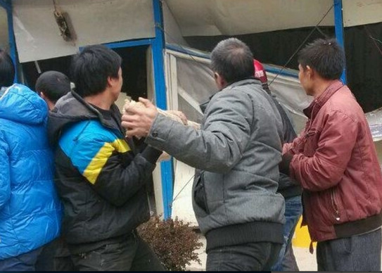 Patru săteni folosesc stâlpi de lemn pentru a sparge birourile Uzinei Electrice Nanshan de pe râul Weijiang în oraşul Guilin, China, 18 noiembrie 2013 (tieba.baidu.com)