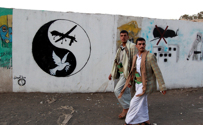 Yemeniţi trecând pe lângă imaginea unei drone desenate în centrul unui simbol yin-yang, în data de 13 decembrie, zi când un convoi de nuntaşi a fost lovit, din greşeală, de o dronă americană. (MOHAMMED HUWAIS / AFP / Getty Images)