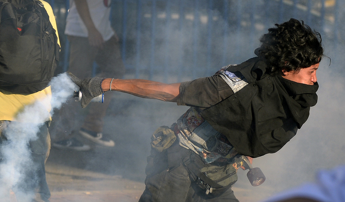 Studenţi aruncând înapoi grenadele cu gaze lacrimogene aruncate înspre ei de poliţişti, în timpul protestelor anti-guvernamentale din Cacaracas, 15 februarie 2014.