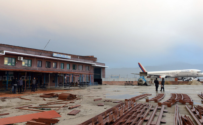 Rezidenţi din Nepal stau în apropierea clădirii terminalului, după ce un avion s-a prăbuşit în partea de nord-vest a văii Kathmandu, la 16 februarie 2014. (PRAKASH MATHEMA / AFP / Getty Images)