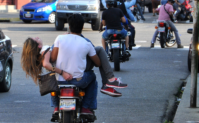 Un tânăr motociclist o duce la spital pe Miss Turism 2013 a statului Carabobo, Genesis Carmona, după ce aceasta a fost împuşcată în cap în timpul unor proteste anti-guvernamentale din statul sud-american. (MAURICIO CENTENO / AFP / Getty Images)