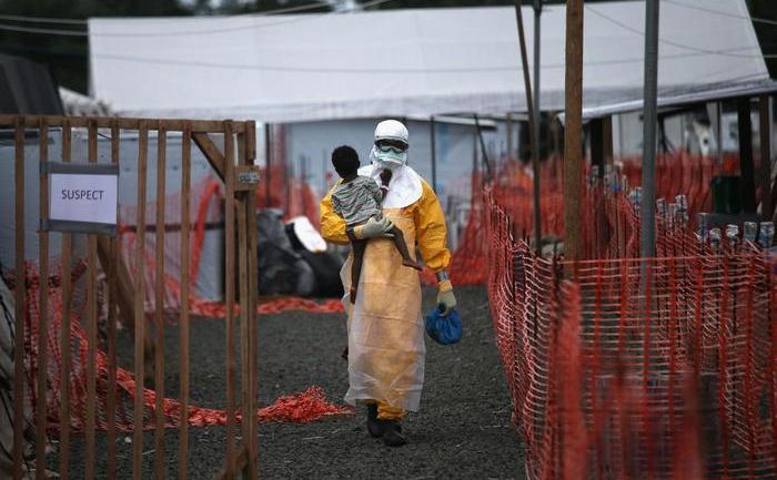 

Un membru al organizatiei Doctori Fără Frontiere (DFF), îmbrăcat într-un costum de protecţie, ţine în braţe un copil suspectat că ar fi infectat cu Ebola în centrul de tratament DFF din Paynesville, Liberia, 5 octombrie 2014.

