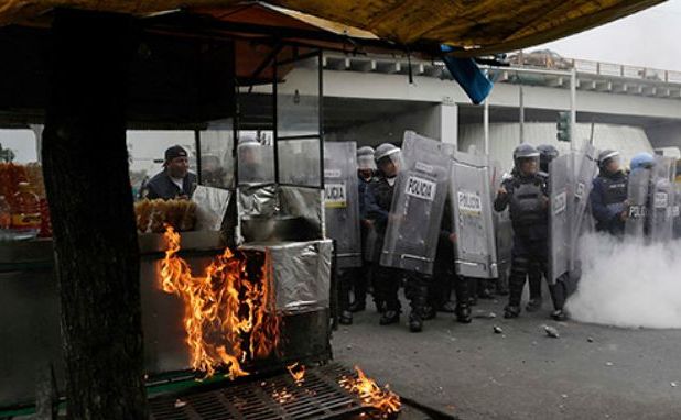 Poliţiştii se apără cu scuturile în timp ce sunt atacaţi de manifestanţi mascaţi la finalul unui marş de protest în Mexico City împotriva răpirii şi chiar uciderii a 43 de studenţi mexicani, 20 noiembrie 2014. (Captură Foto)