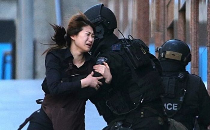 
O tânără fuge din cafeneaua Lindt Chocolat unde un bărbat înarmat a luat mai mulţi ostatici, 15 decembrie 2014, Syndey, Australia.