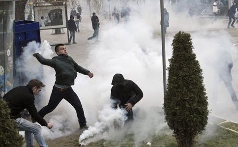 Un manifestant aruncă înapoi o grenadă fumigenă înspre forţele de ordine, în timpul unui protest din capitala kosovara Pristina în 27 ianuarie 2015