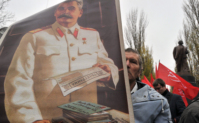 Un portret al lui Iosif Stalin in fata unui monument al lui Lenin, la o parada a comunistilor ucraineni din 7 noiembrie 2013 la Kiev.