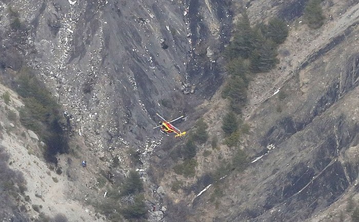 
Un elicopter survolează deasupra locatiei unde s-a prăbuşit avionul Aiburs A320 al companiei Germanwings.