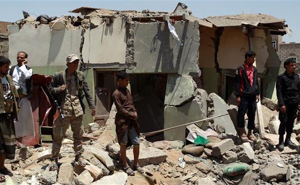 Cetăţeni  yemeniţi se adună în apropierea unor locuinţe distruse de un atac  aerian saudit în apropiere de Aeroportul Internaţional din Sana’a, 31  martie 2015.