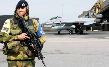 Un soldat păzeşte un avion de luptă F-16 de producţie americana, la baza aeriană Keflavik din Islanda.