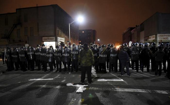 Un  manifestant confruntă poliţiştii în apropiere de departamentul de  poliţie al districtului vestic din Baltimore, în cadrul unor proteste  declanşate în 25 aprilie 2015 de uciderea tânărului de culoare Freddie  Gray de către poliţişti. (Captură Foto)