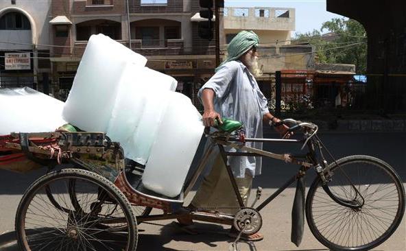 Un indian îşi foloseşte ricşa pentru a transporta gheaţă de la o fabrică de gheaţă din Amritsar, 27 mai 2015.