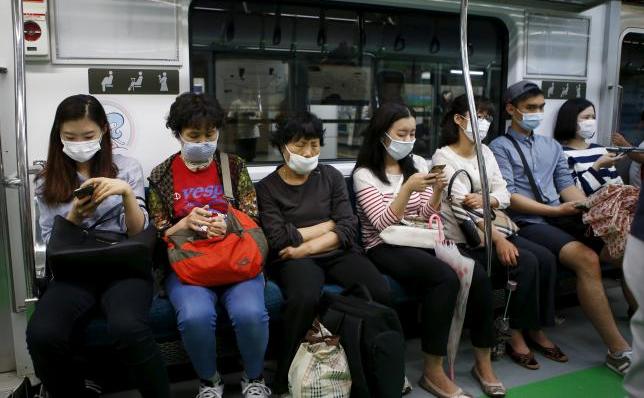 Călătorii poartă măşti de protecţie într-un metrou din Seul pentru a împiedica contractarea virusului MERS, 5 iunie 2015.