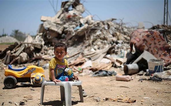Un copil palestinian stă în faţa unei rămăşiţelor unor clădiri distruse în satul Khuza’a, în timpul războiului de 50 de zile purtat de Israel împotriva Fâşiei Gaza în vara anului 2014.