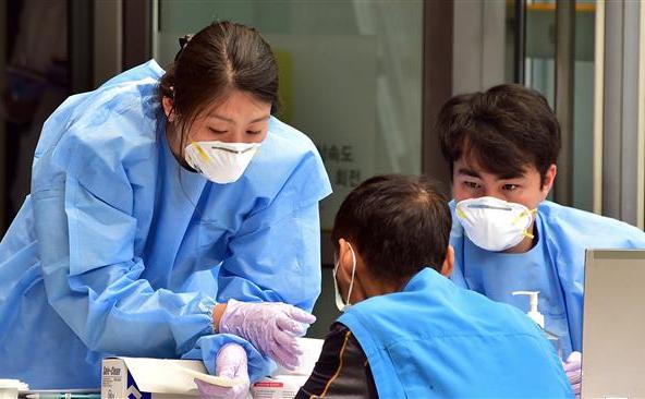 Angajaţi medicali sud-coreeni, care poartă măşti de protecţie, verifică un vizitator la o clinică specială din Seul, 16 iunie 2015.
