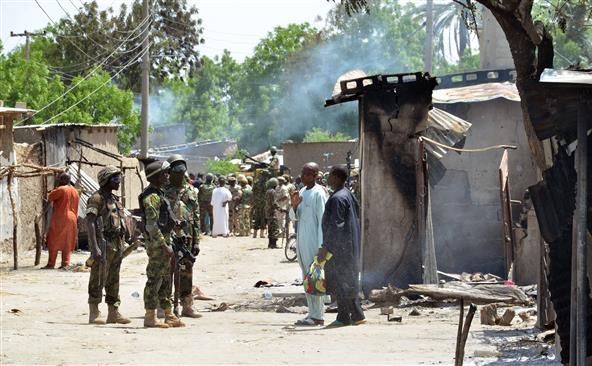 Soldaţii discută cu oamenii în apropierea locuinţelor incendiate de gruparea Boko Haram în satul Zabarmari, 3 iulie 2015, Nigeria.