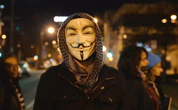 Un manifestant poartă o mască asociată cu grupul de hackeri Anonymous. (Captură Foto)