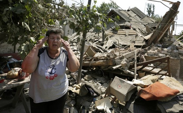 O rezidentă din satul Luganske, regiunea Doneţk, stă lângă locuinţa ei distrusă de un bombardament al forţelor separatiste în 23 iulie 2015.