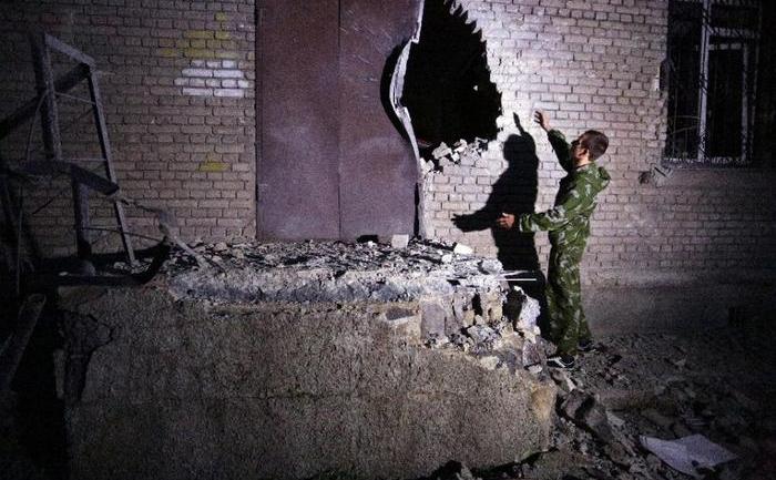 Un bărbat examinează o gaură produsă de un proiectil într-o clădire din oraşul ucrainean Doneţk, 18 iulie 2015. (Captură Foto)